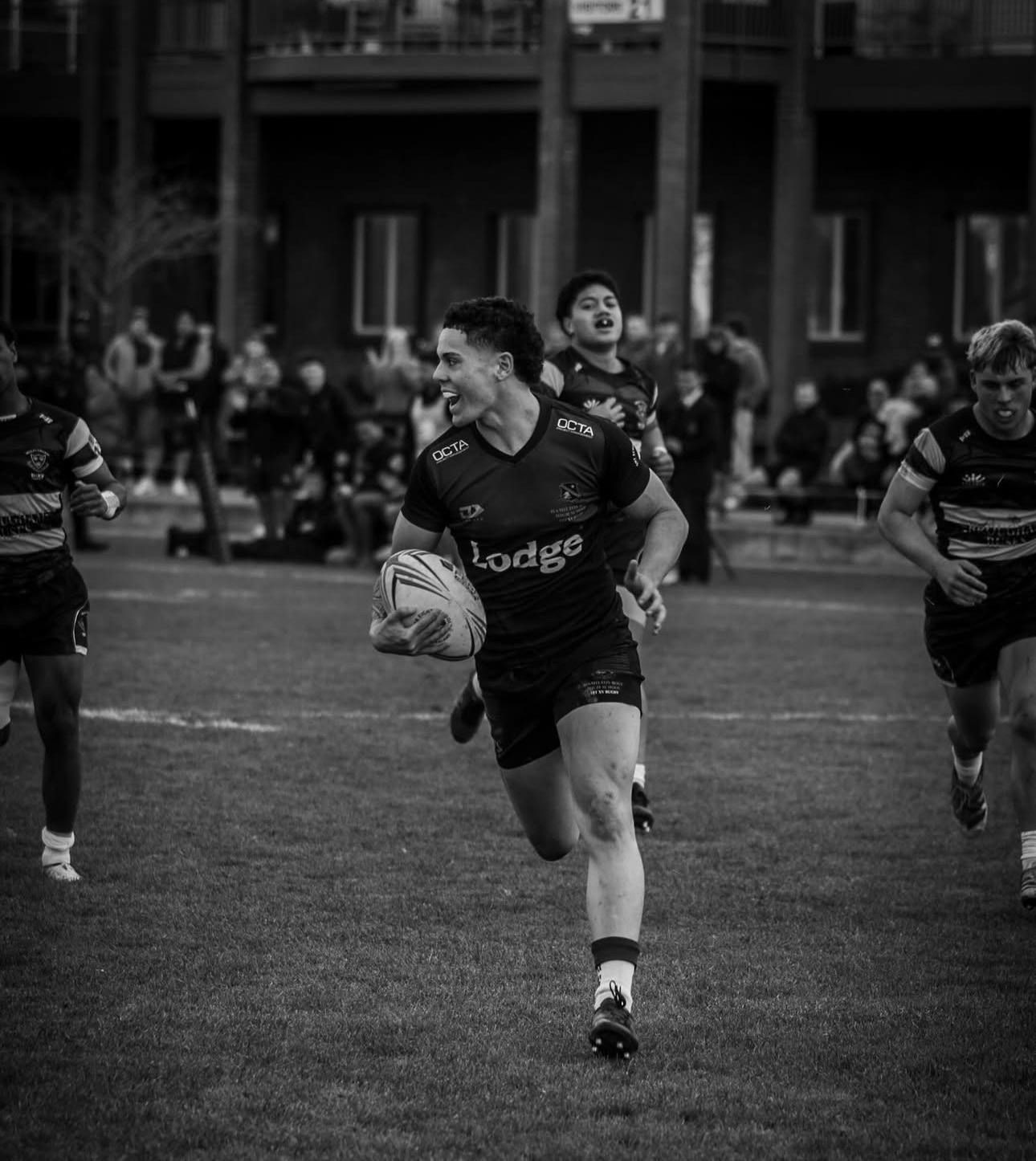 Carson Hunter carrying the ball against Wesley College in black and white